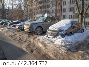 Москва, март. Вросшие в снег и лед машины, стоящие на парковке во дворе многоквартирного дома (2024 год). Редакционное фото, фотограф Наталья Николаева / Фотобанк Лори