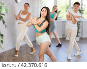 Brunette teenage girl practicing vigorous dance with group in studio. Стоковое фото, фотограф Яков Филимонов / Фотобанк Лори
