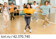 Happy brunette teenage girl practicing vigorous dance with group. Стоковое фото, фотограф Яков Филимонов / Фотобанк Лори
