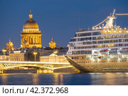 Круизный лайнер Azamara Journey пришвартовался на Английской набережной на фоне Исаакиевского собора в Санкт-Петербурге во время белых ночей (2019 год). Редакционное фото, фотограф Ольга Визави / Фотобанк Лори