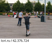 Moscow, Russia - July 26, 2019 Trick at sportive push scooter on a city street. Редакционное фото, фотограф YuryKara / Фотобанк Лори