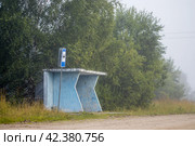 Автобусная остановка в сельской местности. Утренний туман. На автобусной остановке никого нет. Рядом с остановкой установлен дорожный знак. Безлюдная дорога. Окраина села. Стоковое фото, фотограф Андрей Степанов / Фотобанк Лори