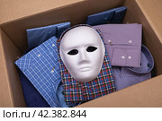 White mask and various shirts in an open cardboard box, concept on the theme of smuggling. Стоковое фото, фотограф Сергей Чайко / Фотобанк Лори