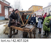 Крутицкое патриаршее подворье.Празднование традиционного русского зимнего праздника Масленица.Ярмарочная площадь.Кузнец раздувает меха и рассказывает зрителям истории.Москва. Россия. (2024 год). Редакционное фото, фотограф Мария Фетисова / Фотобанк Лори