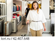 Happy woman chose suitcase in haberdashery store. Стоковое фото, фотограф Яков Филимонов / Фотобанк Лори