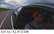 Автомобиль едет по автостраде. Вид со стороны автомобиля на обочину. Гиперсюжеты. В салоне сидят два человека, мужчина и женщина. Вечернее время. Семья путешествует на автомобиле по стране. Стоковое видео, видеограф Воловодов Владимир / Фотобанк Лори