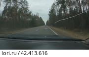 Автомобиль едет по асфальтированной дороге за городом. Вид с пассажирского сиденья. На обочине узкой дороги растут зеленые ели. Серое небо. Трещина в стекле. Путешествие на автомобиле. Стоковое видео, видеограф Воловодов Владимир / Фотобанк Лори