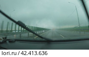 Автомобиль едет по автостраде в дождь. Вид из салона автомобиля. Лобовое стекло покрыто каплями дождя, дворники работают быстро. Плохая видимость. Путешествие на автомобиле в плохую погоду. Стоковое видео, видеограф Воловодов Владимир / Фотобанк Лори