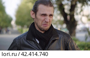 Young man in black jacket expressing disgust and disapproval with negative facial expressions outdoors. Стоковое видео, видеограф EStarodubov / Фотобанк Лори
