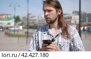 Front view of a perplexed man with a small beard walking checking smart phone content. Стоковое видео, видеограф EStarodubov / Фотобанк Лори