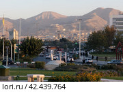 People, cars and motorcycles on the street in the center of Tehran near The Azadi Tower, Iran (2023 год). Редакционное фото, фотограф VittoriaChe / Фотобанк Лори