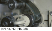 Close-up of a 35mm cine-film in movie projector. Clamping guide rollers and gear drums. Стоковое видео, видеограф EStarodubov / Фотобанк Лори