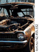 Close-up completely burnt out and carbonized car. Vehicle blown up by military shell burned abandoned automobile during war operations. Copy space. Стоковое AI-изображение, AI-художник Aleksandr Golubev / Фотобанк Лори