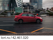 Red Nissan Tiida is driven on rainy wet road. Car speeding on slippery asphalt highway. Редакционное фото, фотограф Константин Григорьев / Фотобанк Лори