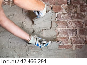 Construction and repair. a man with two trowels in his hands is plastering an old brick wall with a cement-sand mixture. Стоковое фото, фотограф Коханова Наталья / Фотобанк Лори