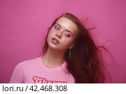 Рыжеволосая девушка позирует в студии на розовом фоне. Стоковое фото, фотограф Земскова Елена / Фотобанк Лори