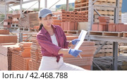 Woman with document in construction material storage. Стоковое видео, видеограф Яков Филимонов / Фотобанк Лори