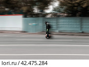 Man on an electric unicycle riding fast on street. Driving around the city on an electric monowheel. Редакционное фото, фотограф Константин Григорьев / Фотобанк Лори