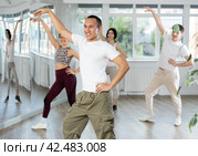 Cheerful Asian fitness instructor leading Zumba class. Стоковое фото, фотограф Яков Филимонов / Фотобанк Лори
