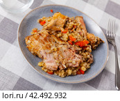 Lunch is served on plate - baked pieces of young rabbit and pearl barley. Стоковое фото, фотограф Яков Филимонов / Фотобанк Лори
