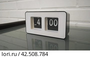 Перекидной циферблат часов будильника. Монтаж двух планов. Flip clock mechanism. 4:00 PM. Flip clock watch face. White brick wall in the background. Slow motion 240 fps. Стоковое видео, видеограф EStarodubov / Фотобанк Лори