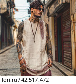 Stylish man on the street in rustic oversize thin fabric beige tank top with subtle burgundy paisley details,    Generative AI. Стоковое AI-изображение, AI-художник Анна Кривицкая / Фотобанк Лори