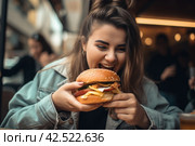 Happy plus size model eats with pleasure a big hamburger in a cafe, fat woman leads an unhealthy lifestyle and gains excess weight, AI Generated. Стоковое AI-изображение, AI-художник Станислав Тарко / Фотобанк Лори