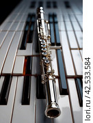 Flute with piano. Flute on piano keys. Wind instrument for musical design of concert creativity. Стоковое AI-изображение, AI-художник Aleksandr Golubev / Фотобанк Лори