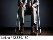 Battered Man injured leg using crutches. Generate Ai. Стоковое AI-изображение, AI-художник Иван Рябоконь / Фотобанк Лори