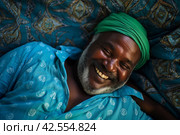 From an aerial perspective, a man lies in bed under a turquoise blanket, with his head resting on coordinating pillows. Стоковое AI-изображение, AI-художник Юлия Гапеенко / Фотобанк Лори