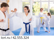 Woman in kimono honing punching techniques during kumite with man. Стоковое фото, фотограф Яков Филимонов / Фотобанк Лори