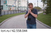 Tourist travel photographer lights up a cigarette on the city street. Стоковое видео, видеограф EStarodubov / Фотобанк Лори