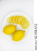 Yellow ripe and juicy fruits of lemons on a white plate. Sliced lemons close-up. Delicious lemons for tea. Lemon slices. Стоковое фото, фотограф Valeriy Lushchikov / Фотобанк Лори