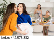 Hospitable hostess kissing female friends arriving for home get-together. Стоковое фото, фотограф Яков Филимонов / Фотобанк Лори