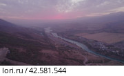 The drone flies next to the cabins of the funicular in the mountains, next to a mountain river and a small town at the foot. Стоковое видео, видеограф Aleksey Kidisyuk / Фотобанк Лори
