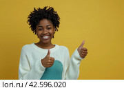 ctp afroamerican young woman in white sweater with thumbs up while pointing to right. Стоковое AI-изображение, AI-художник Юлия Гапеенко / Фотобанк Лори