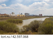 Город Уссурийск, Приморский край, Россия. Вид на реку Раковка, протекающую в городе Уссурийске. Вдали жилые здания. Весенний городской пейзаж. (2023 год). Стоковое фото, фотограф Андрей Степанов / Фотобанк Лори