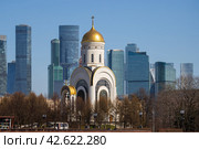 Церковь Георгия Победоносца, Поклонная гора, Москва, Россия. Вид на церковь и небоскрёбы московского международного делового центра «Москва-Сити». Современный городской пейзаж. Красивая церковь на фоне высотных зданий. (2023 год). Редакционное фото, фотограф Андрей Степанов / Фотобанк Лори