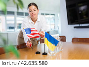 Female office coordinator placing flags of Ukraine and United States on table. Стоковое фото, фотограф Яков Филимонов / Фотобанк Лори