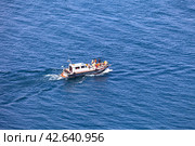 BAIKAL LAKE, OLKHON ISLAND, USYK VILLAGE, IRKUTSK REGION, RUSSIA - August 15, 2023: Top view of group of tourists travels along Small Sea on pleasure boat around Olkhon Island on summer day. Редакционное фото, фотограф Виктория Катьянова / Фотобанк Лори