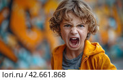 Expressive young boy with curly hair shouting, wearing a yellow jacket and showing anger on his face. Стоковое AI-изображение, AI-художник Юрий Поздников / Фотобанк Лори