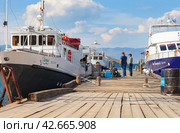 BAIKAL LAKE, OLKHON ISLAND, SAKHYURTA VILLAGE, IRKUTSK REGION, RUSSIA - August 14, 2023: A group of tourists going on a water cruise on a ship around Baikal Lake on a sunny summer day. Редакционное фото, фотограф Виктория Катьянова / Фотобанк Лори