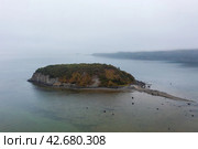 Вид с воздуха на небольшой остров в морской бухте. Осенний сезон. Пасмурная погода. Низкая облачность. Начало отлива. Остров Вдовушка, бухта Весёлая, Охотское море, Магаданская область, Дальний Восток России. Стоковое фото, фотограф Андрей Степанов / Фотобанк Лори