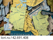 Части пазла в виде субъектов Российской федерации с карты страны на прилавке книжного магазина в городе Москве, Россия (2024 год). Редакционное фото, фотограф Николай Винокуров / Фотобанк Лори