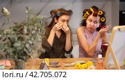 Female friends enjoying moments of beauty routine and self care. Women sitting by table top mirror in colorful curlers, applying facial mask with brush and under-eye patches. Стоковое видео, видеограф Яков Филимонов / Фотобанк Лори