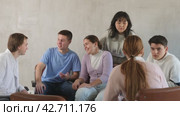 Exited adult students engaged in discussion sitting on chairs in circle in light room. Стоковое видео, видеограф Яков Филимонов / Фотобанк Лори