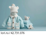 Stack of baby knitted clothes and teddy bear toy on table. Set of newborn child rompers, hat and jumper. Fashion infant accessories isolated pastel blue background, empty space. Kid's toys and clothes. Стоковое AI-изображение, AI-художник Марина Демидюк / Фотобанк Лори