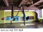 A woman performs the Vasishthasana exercise in a hammock, side plank pose, training alone in sportswear. Стоковое фото, фотограф Сергей Чайко / Фотобанк Лори