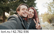 Lovely young couple is taking photo themselves outdoors in the autumn city park. Стоковое видео, видеограф EStarodubov / Фотобанк Лори