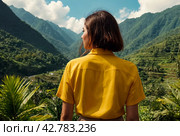 Rear view of lady enjoy at landscape Adam's peak mountain at tropical journey Sri Lanka, Ella, posing. From behind of adult woman in yellow jacket at landmark nature background. Copy ad text space. Стоковое AI-изображение, AI-художник Aleksandr Golubev / Фотобанк Лори